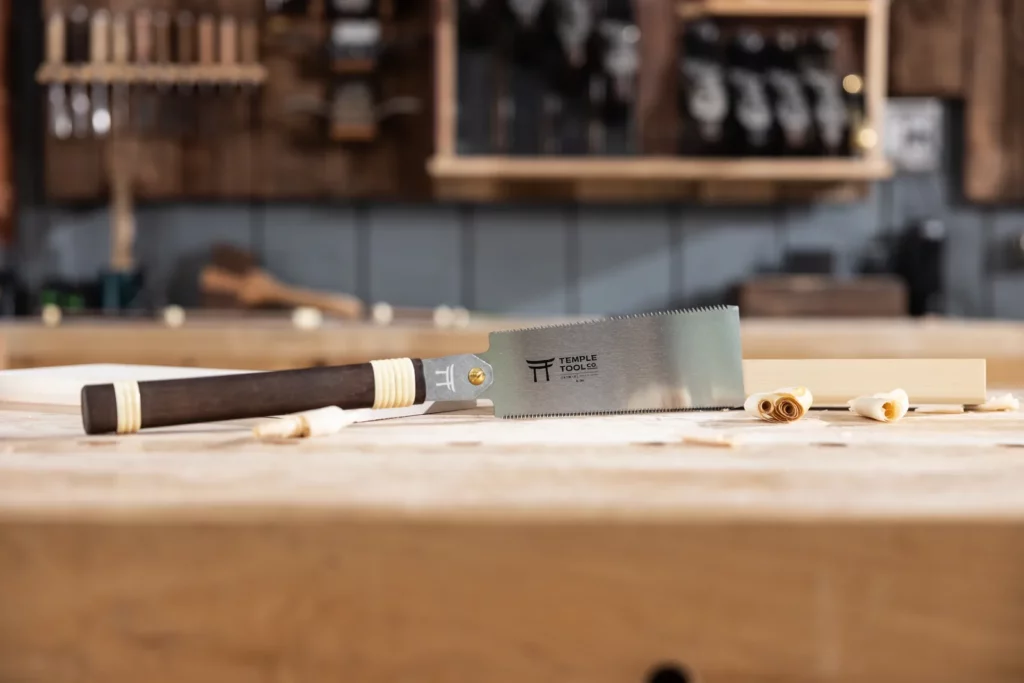 Temple Tool 180mm 雙刃鋸放在工作桌上,背景為木工工具牆